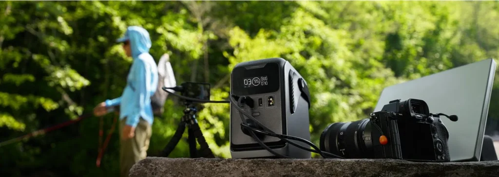 EcoFlow TRAIL 300 DC на камені біля води живить фотоапарат та іншу техніку через USB-C